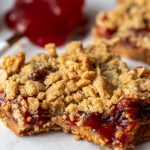 peanut butter and jelly crumble bars with a spoonful of jelly in the background