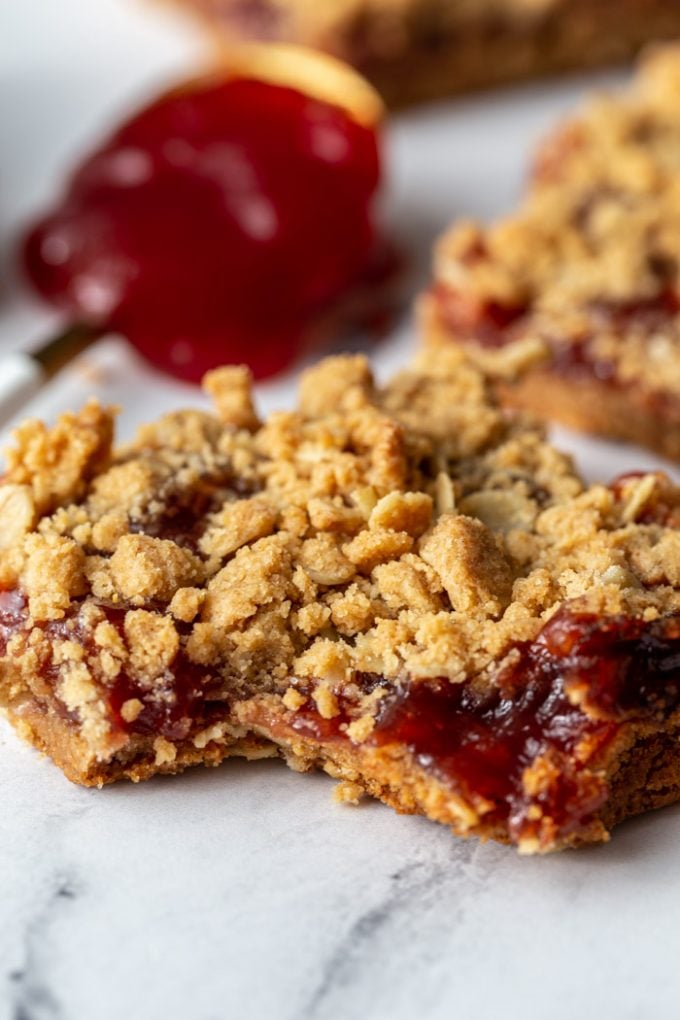 peanut butter and jelly crumble bars with a spoonful of jelly in the background