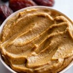 creamy date paste in a small bowl with fresh dates around the bowl
