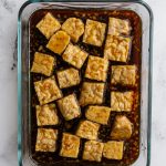 glass container with tempeh marinating in a dark sauce