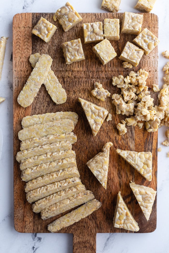 tempeh on a wood cutting board and cut into several different shapes