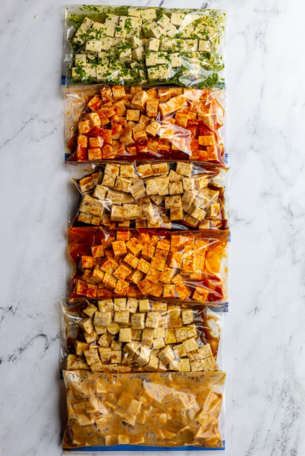 6 gallon baggies filled with tofu cubes and varies flavors and colors of tofu marinade