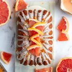 Iced grapefruit loaf topped with slices of grapefruit and more grapefruit around the loaf