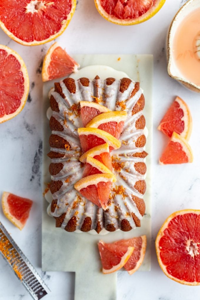 Iced grapefruit loaf topped with slices of grapefruit and more grapefruit around the loaf
