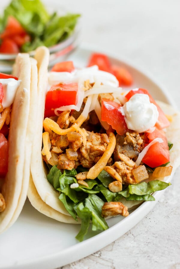 tempeh tacos on a flour tortilla with cheese and fresh veggies on top