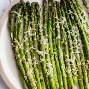 air fryer asparagus topped with parmesan cheese on a serving plate