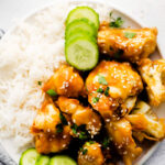plate filled with white rice, cucumber, and sticky sesame cauliflower