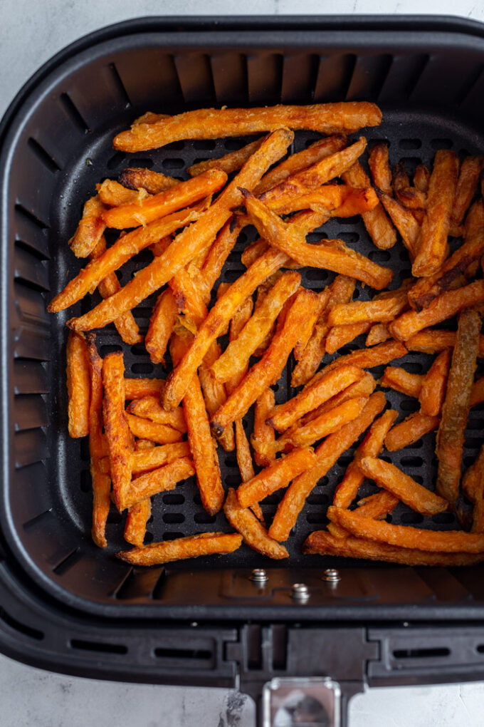 black basket of an air fryer with cooked sweet potato fries in it