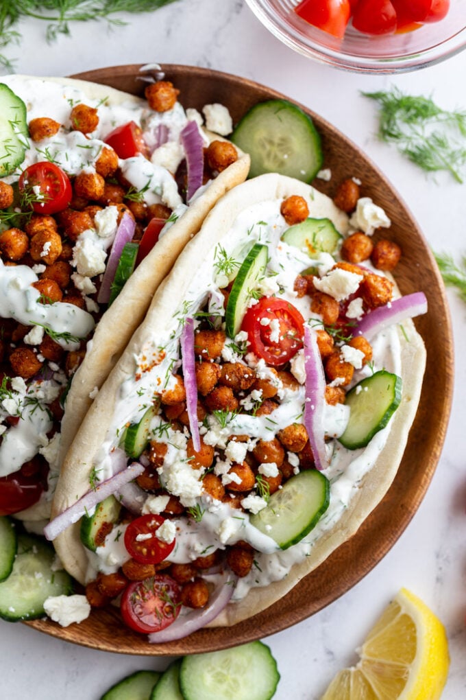 gyro made with crispy chickeas topped with red onion and feta cheese. on a wood plate
