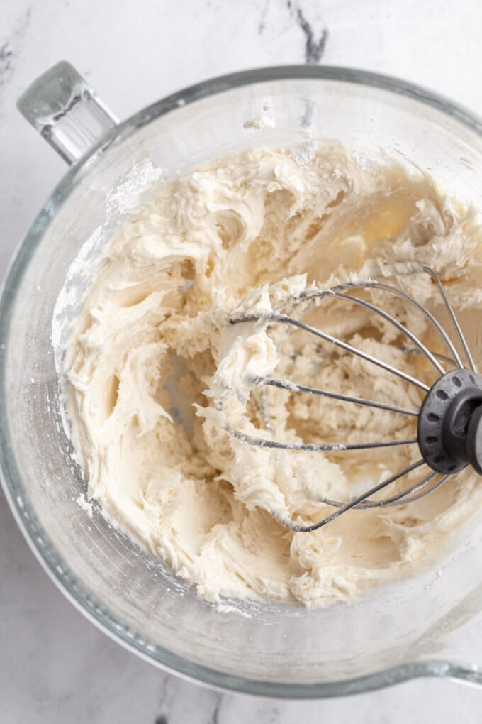 buttercream cookie frosting in the base of a stand mixer with the whisk attachment sitting in the bowl