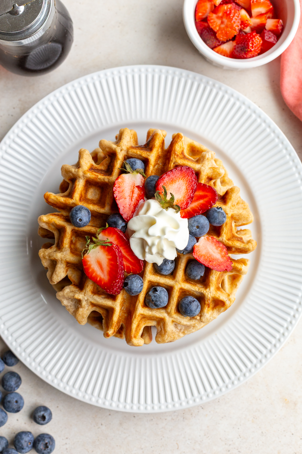 Vegan waffles topped with fresh strawberries, blueberries and a dollop of whipped cream.