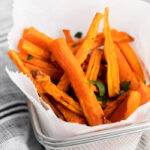 basket lined with parchment paper and filled with carrot fries that have been sprinkled with herbs