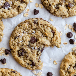 chocolate chip oatmeal cookies on parchment paper with oats and chips surrounding it