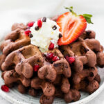 chocolate waffles topped with whipped cream and strawberries