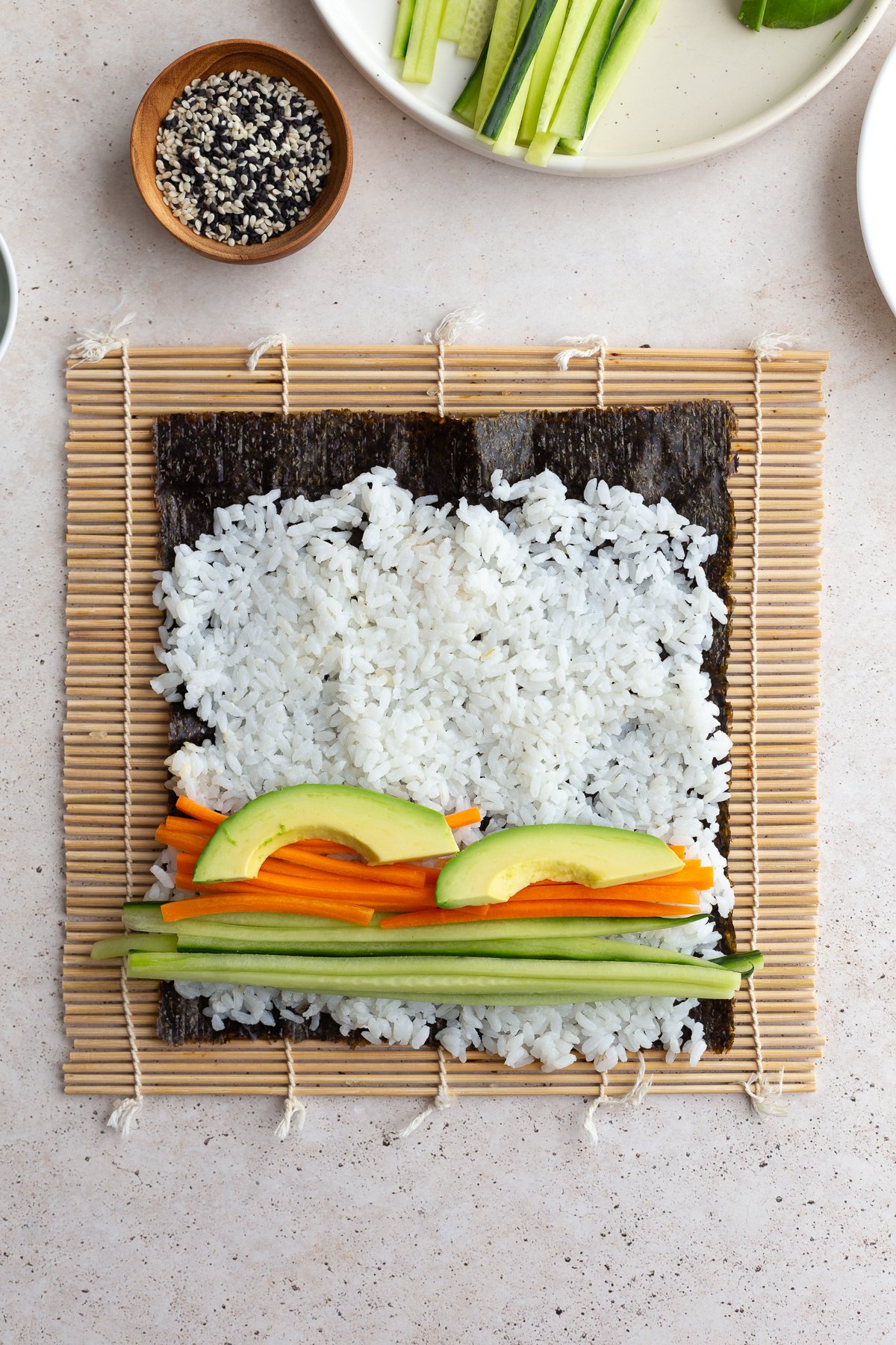 Rice on a nori sheet topped with strips of carrots, cucumber and avocado.