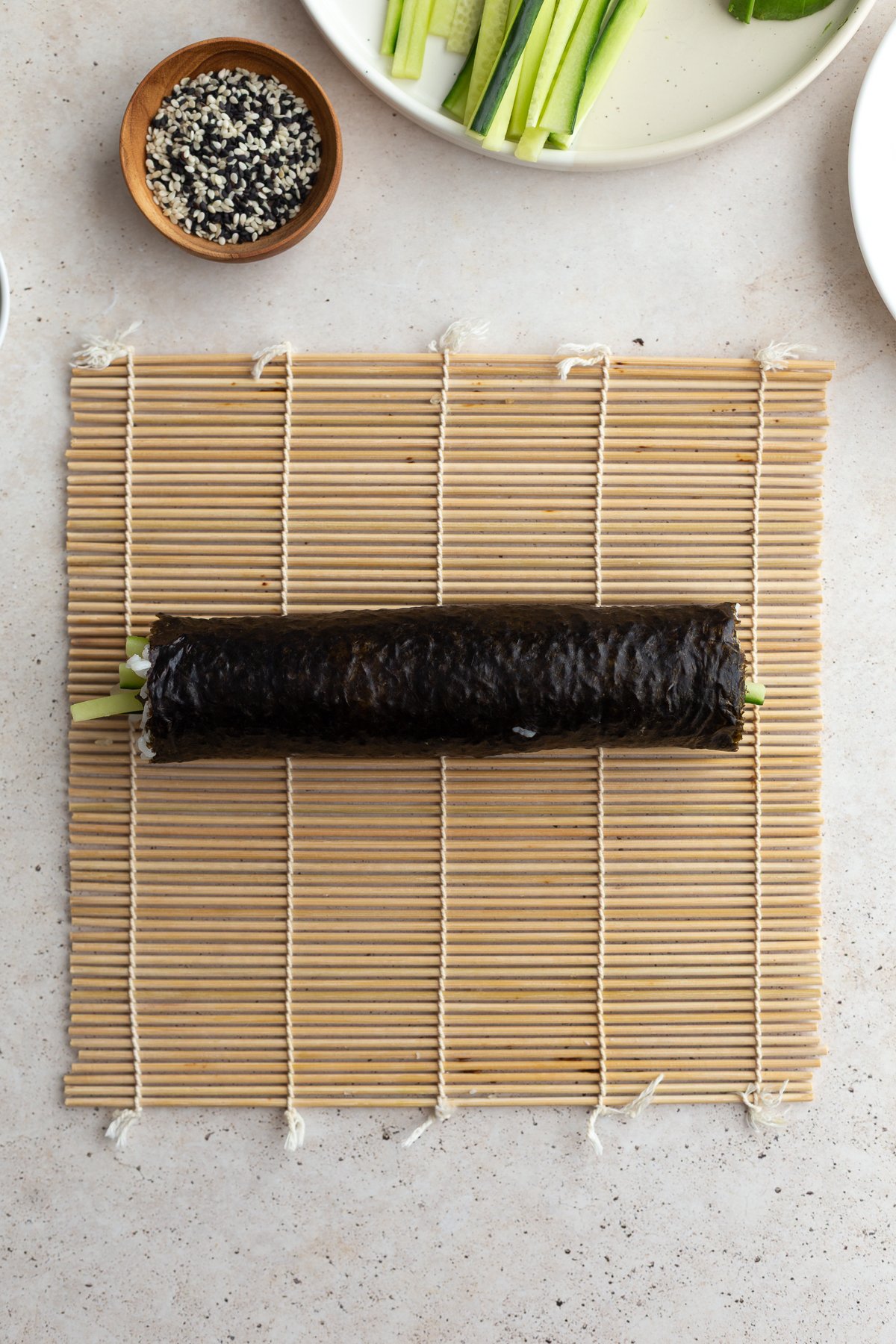 Sushi roll rolled up on a sushi mat.