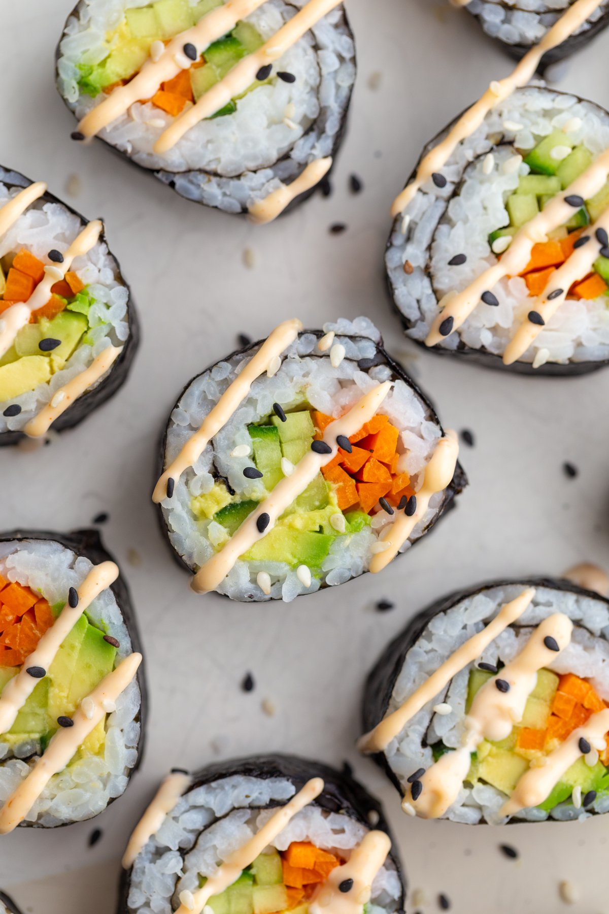 Cucumber roll filled with avocado and pickled carrot and drizzled with spicy mayo.