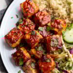 large white dish with quinoa and coleslaw in the corner with the highlight being large cubes of bbq tofu