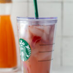 starbucks pink drink in a starbucks cup with freeze dried strawberries and ice in it