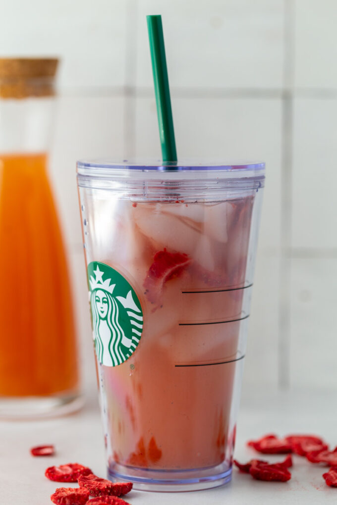 starbucks pink drink in a starbucks cup with freeze dried strawberries and ice in it