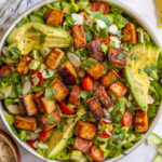 tofu salad topped with sliced avocado and cherry tomatoes