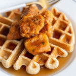 waffle on a white plate topped with vegan chicken nuggets