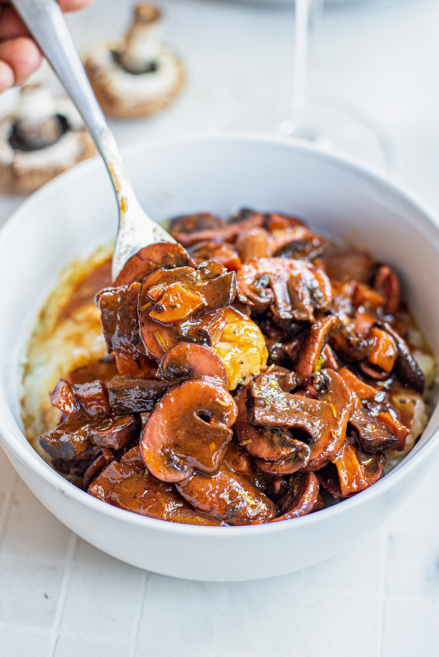 fork in a bowl of mushrooms bourguignon served over mashed potatoes