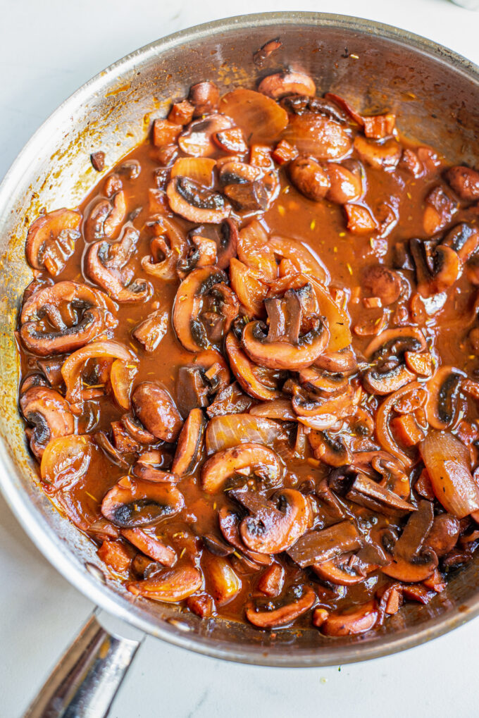 mushrooms cooking in a sauce in a large skillet