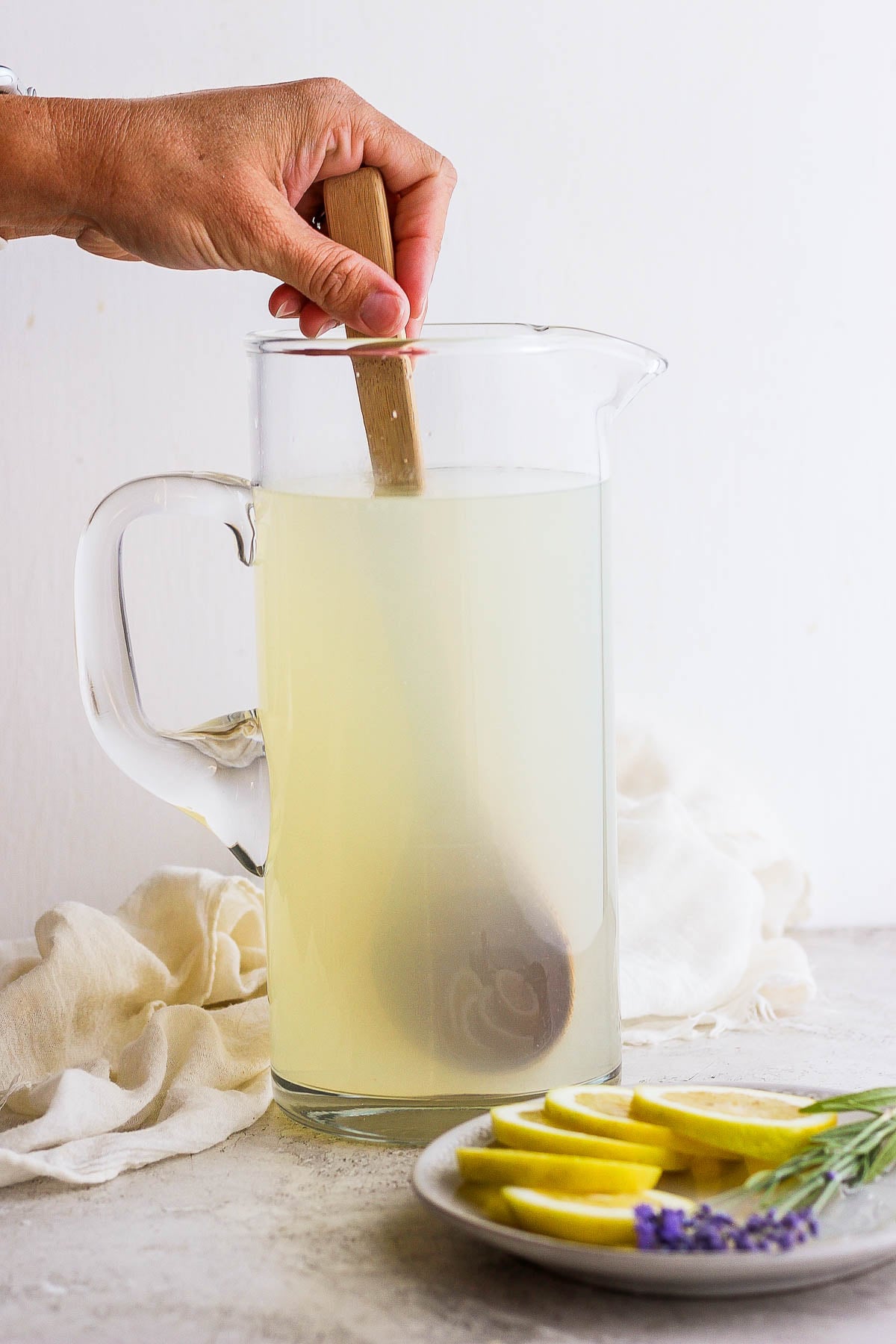 lemonade being stirred with a wooden spoon in a pitcher