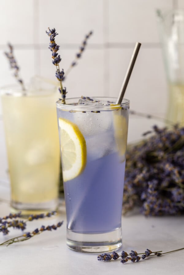 lavender lemonade in a glass with a slice of lemon and a sprig of lavender