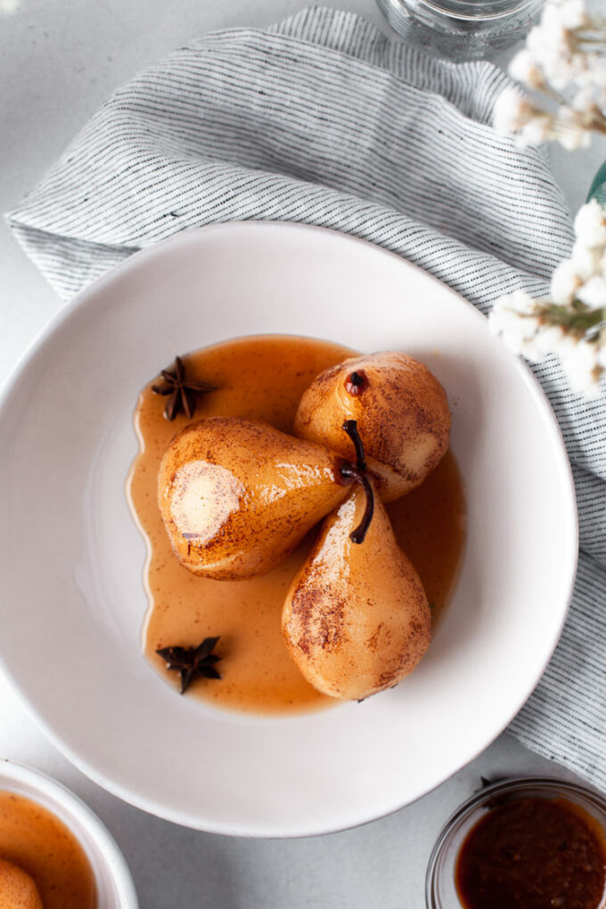 three poached pears in a small white bowl