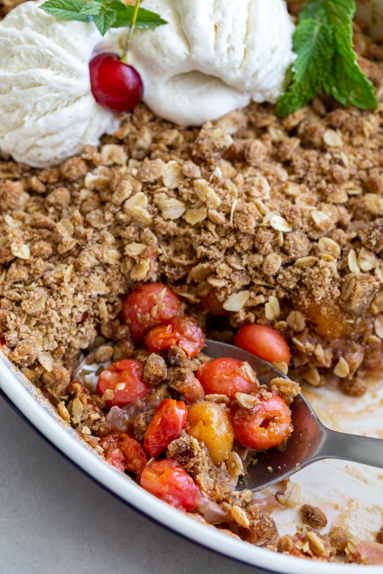 spoon scooping into cherry crisp