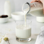 pouring homemade hemp milk into a glass
