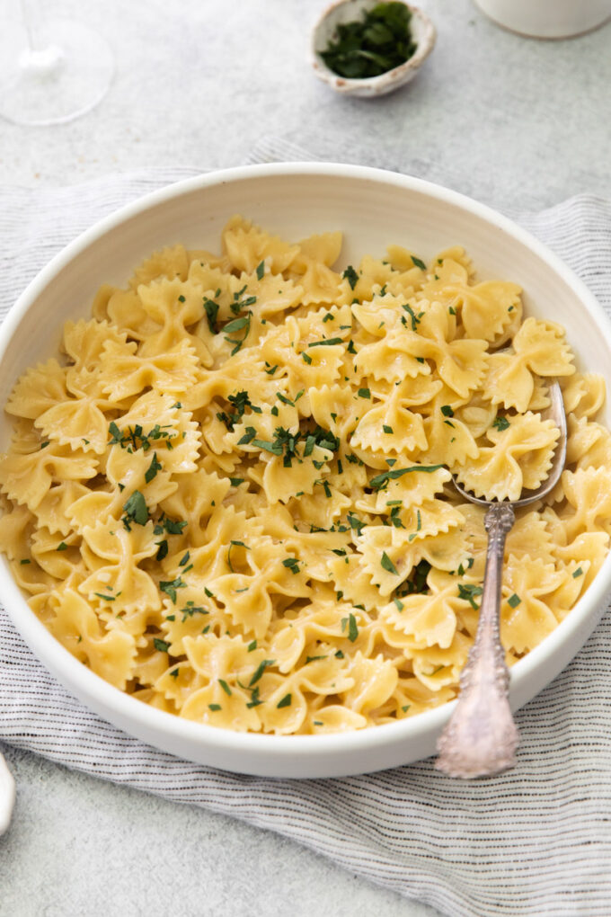 large white bowl filled with bowtie pasta in a white wine sauce