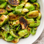 Sautéed Brussels sprouts in a white serving bowl.