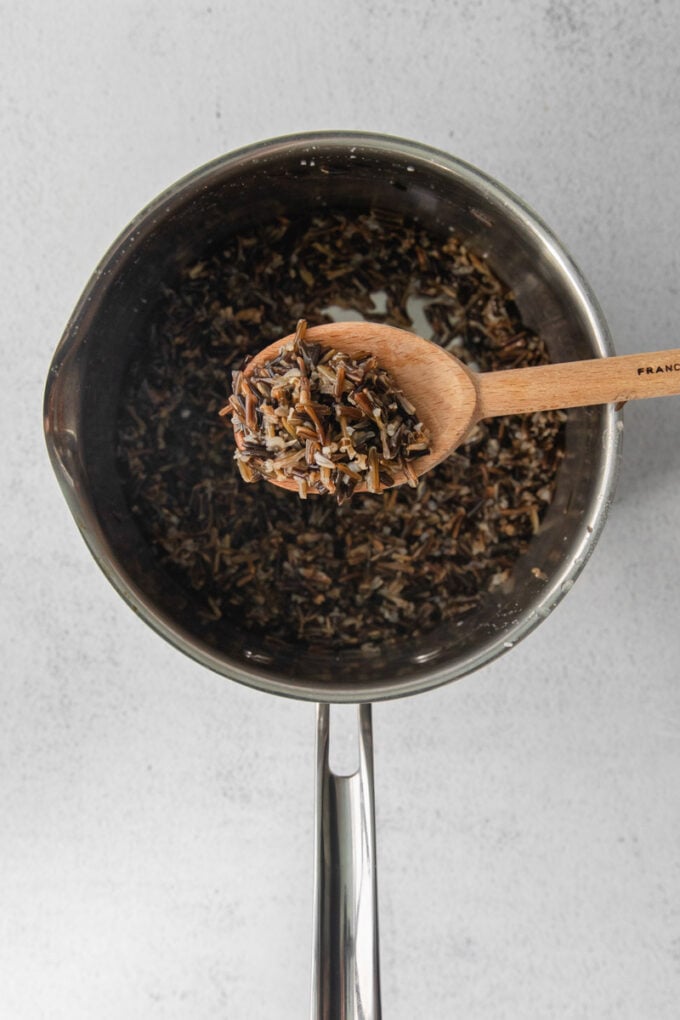 serving wild rice out of a pot with a wooden spoon