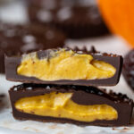pumpkin peanut butter cup cut in half with a small pumpkin in the background