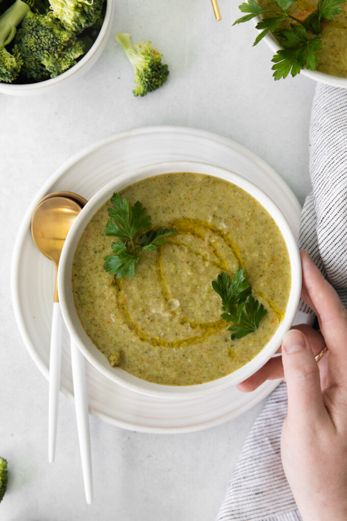 vegan broccoli soup in a white bowl drizzled with oil and topped with fresh parsley