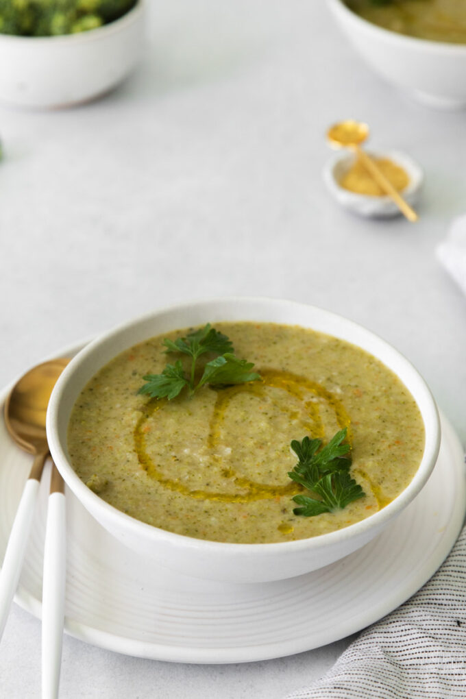 vegan broccoli souping a white bowl with a gold spoon