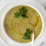 vegan broccoli soup served in a white bowl with a garnish of parsley