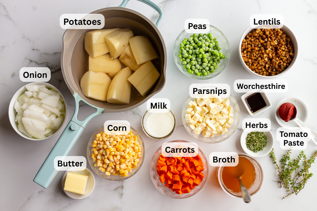 labeled ingredients needed to make vegetarian shepherds pie including lentils, peas, carrots, corn, potatoes, herbs, butter, and broth