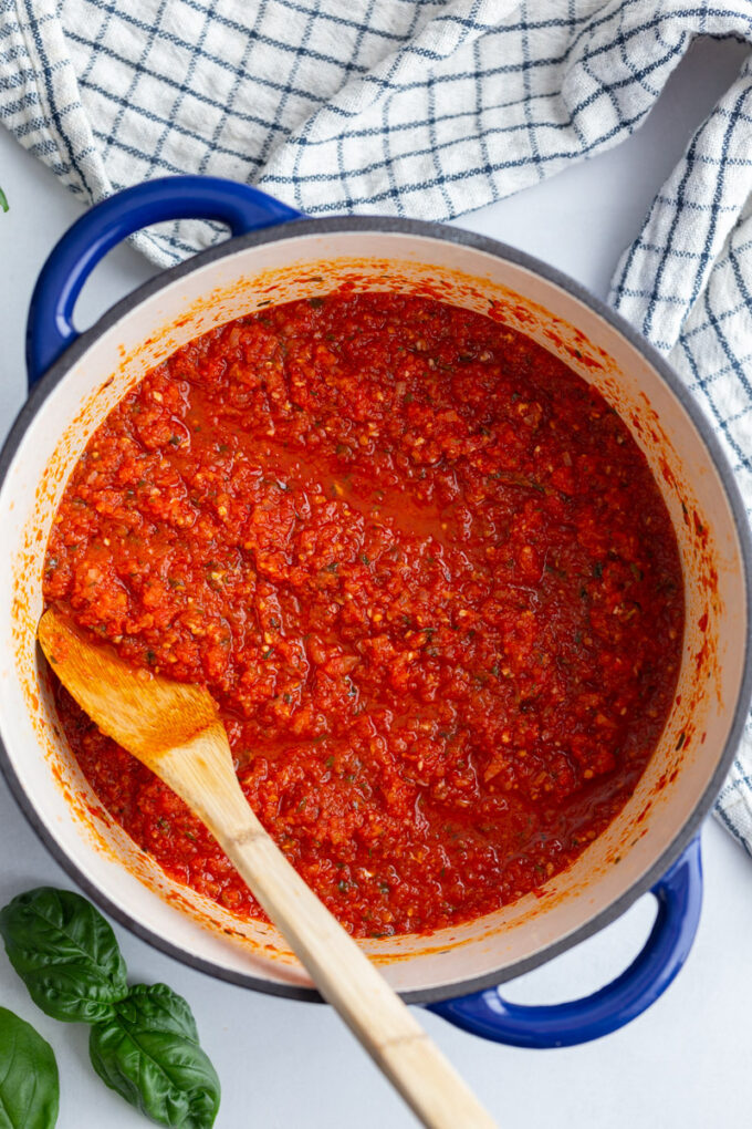 stirring pasta sauce with a wooden spoon