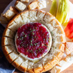 baked brie topped with cranberry sauce inside of a round loaf of bread