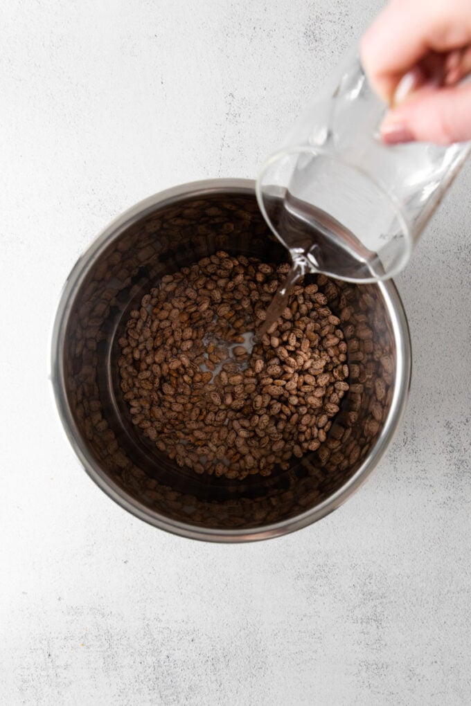 pouring water into Instant Pot with pinto beans