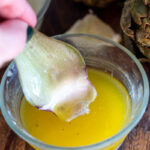 piece of artichoke being dipping in lemon butter