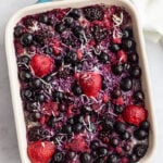 mixed berry topped baked oatmeal in a green staub casserole dish