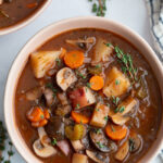vegan stew served in a small white bowl with fresh thyme