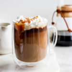 Caramel latte topped with whipped cream and caramel drizzle.