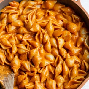 Stirring pasta and sauce in a large skillet.
