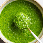 Using a spoon to serve Chimichurri sauce.